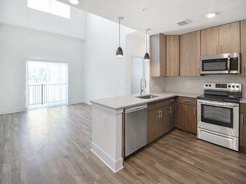 an empty kitchen with stainless steel appliances and wooden cabinets